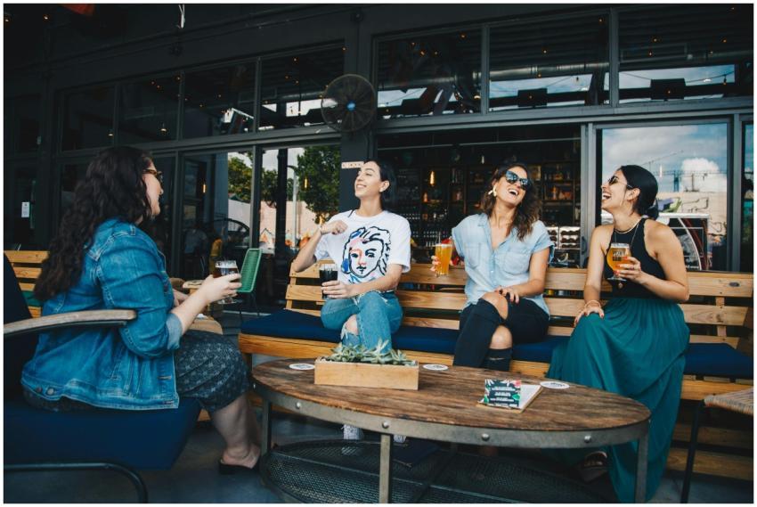 Four friends laughing and enjoying drinks together
