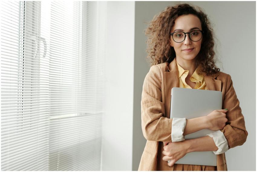 Curly-haired businesswoman wearing glasses holds a