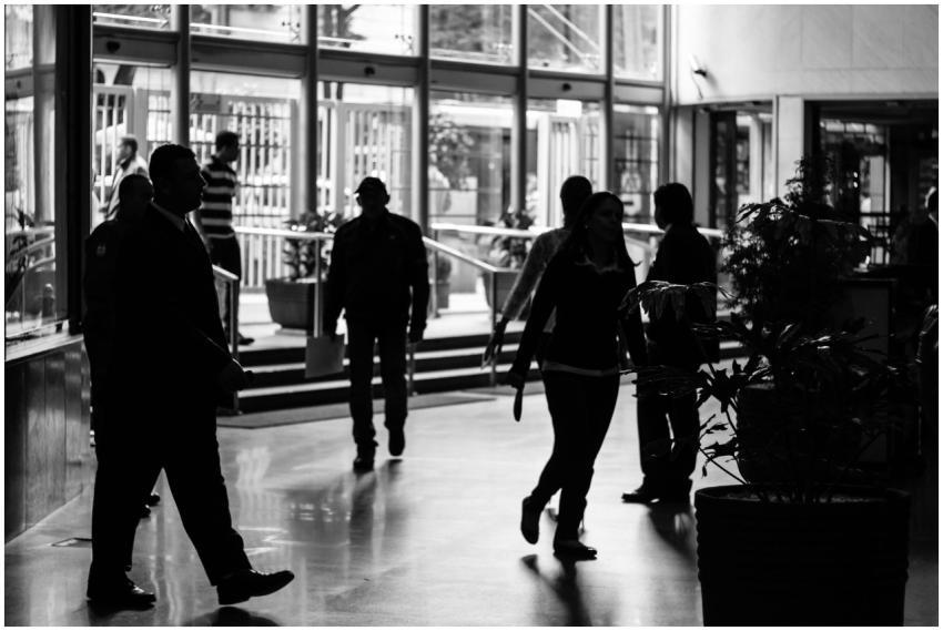 Silhouetted figures walk through a busy indoor lob