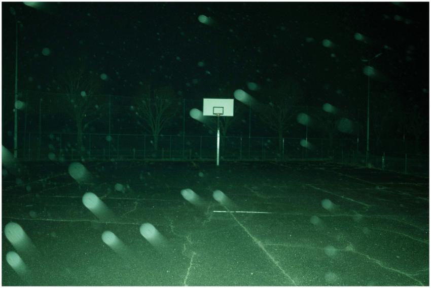 Abandoned basketball court at night with fog creat