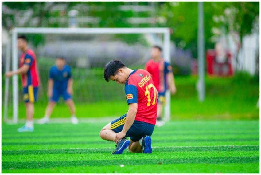 Young football player ties shoe on a sports field