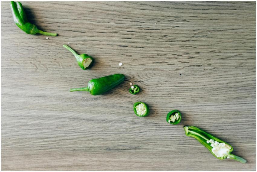 Fresh green chilies sliced and laid on a wooden su