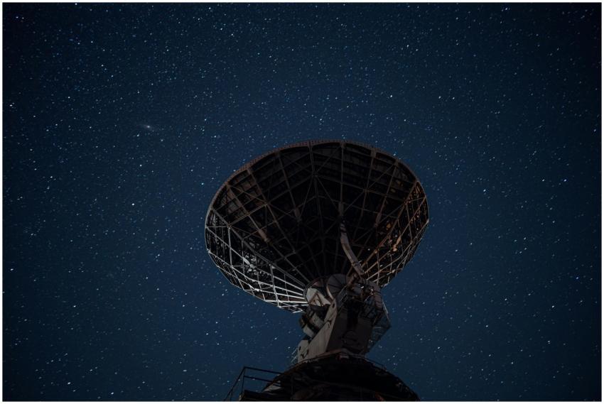 Silhouette of a satellite dish against a starry ni