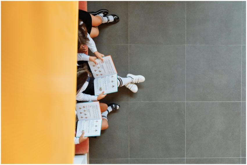 Children reading books on a school bench, viewed f