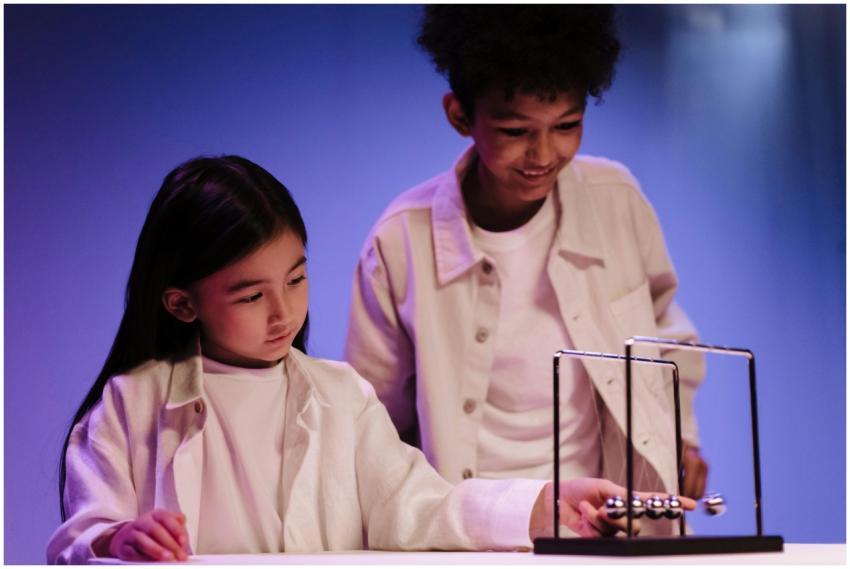 Diverse teenagers engaging with Newton's cradle, e