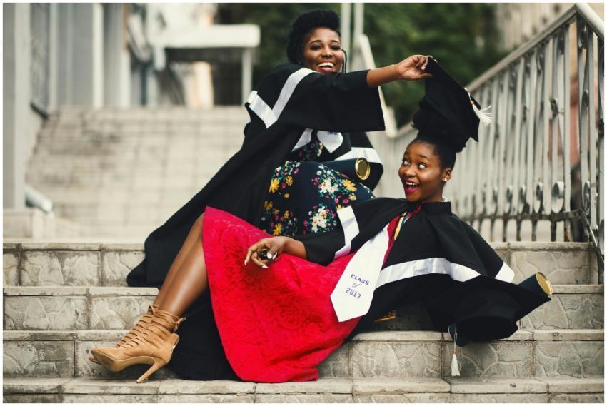 Two women in graduation gowns celebrating on stair