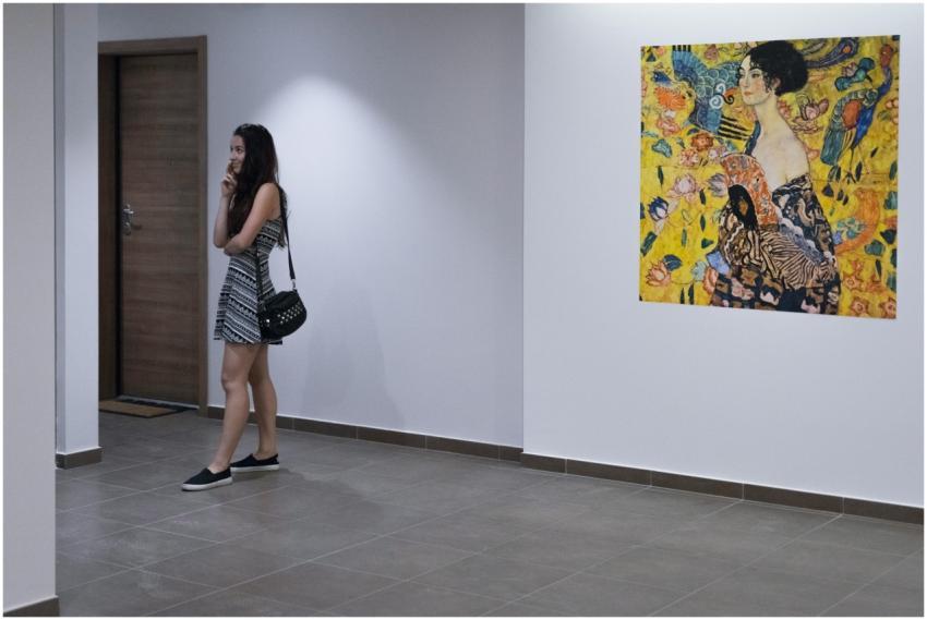 A young woman in a striped dress observes an artwo
