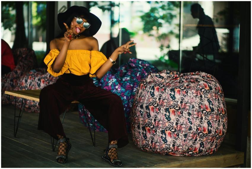 Fashionable woman in yellow top poses with peace s
