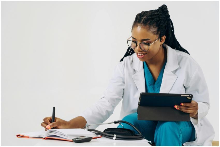 Smiling female doctor in scrubs using tablet and t