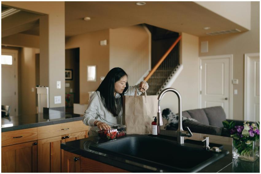 A woman stands in a modern kitchen unpacking groce