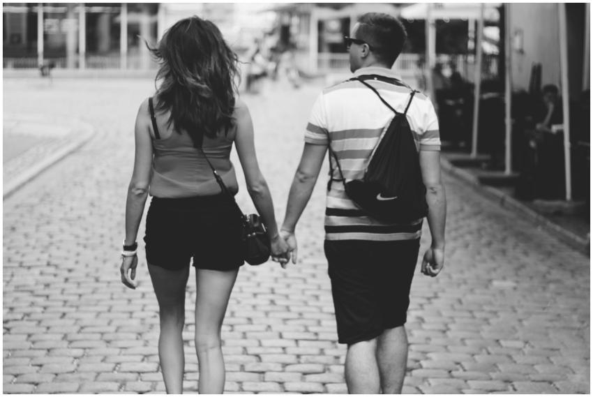 A couple walks hand in hand on a cobblestone stree