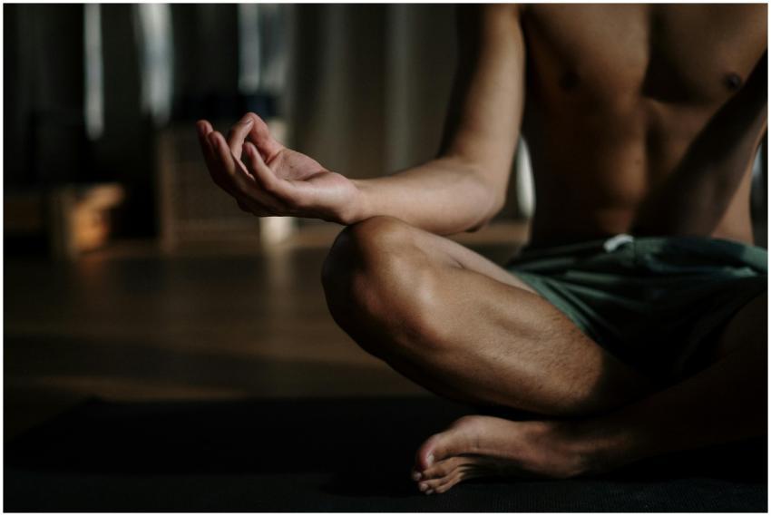 A shirtless man in a yoga studio meditating in the