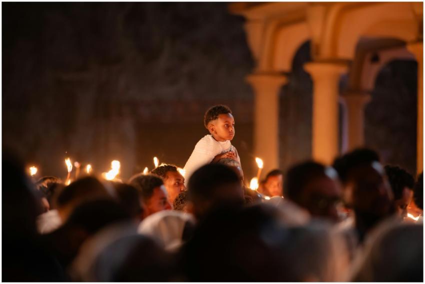A boy on shoulders during a candlelit service at a