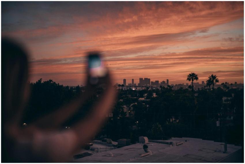 A person photographing the Los Angeles skyline dur