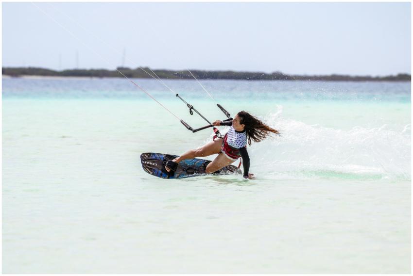A woman skillfully kite surfing on clear turquoise