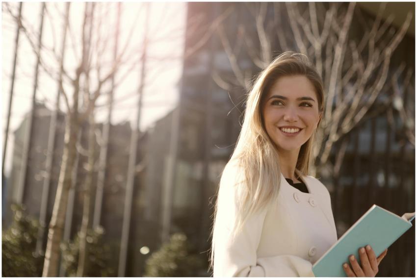 Confident woman smiling with a notebook in outdoor