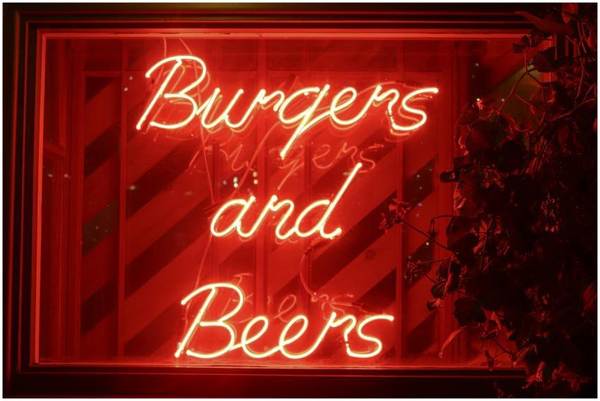 Vibrant red neon sign advertising 'Burgers and Bee