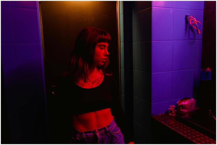 A woman in a dimly lit bar interior with vibrant p