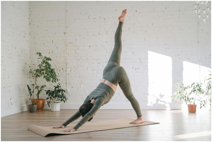 A woman performs a yoga pose on a mat in a sunlit