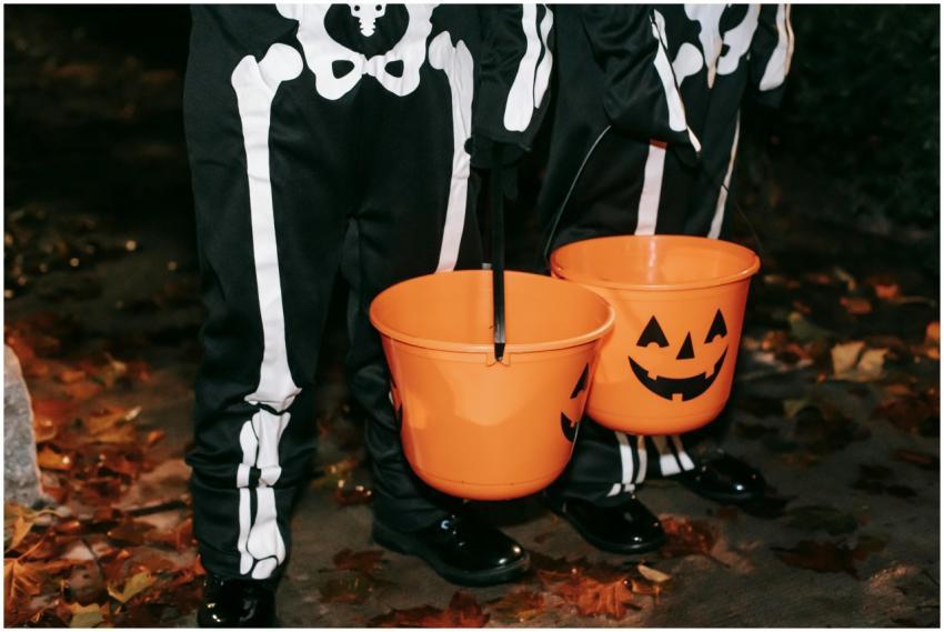 Children dressed in skeleton costumes holding jack
