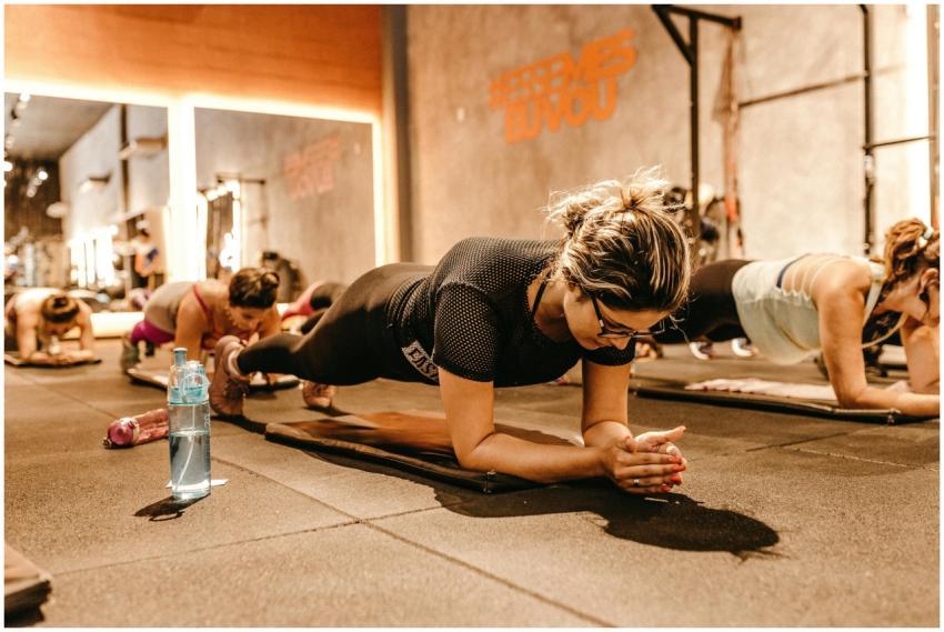 Women practicing planks in a well-lit gym setting,