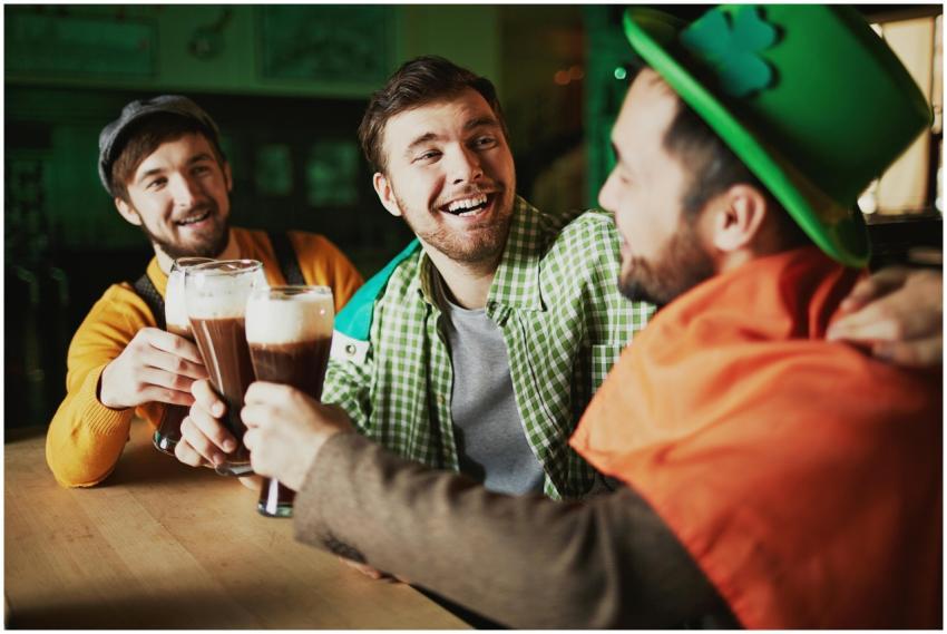 Three friends enjoy drinks, celebrating St. Patric