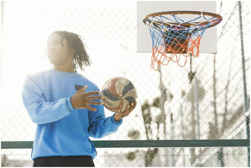 Young athlete casually holding basketball near hoo