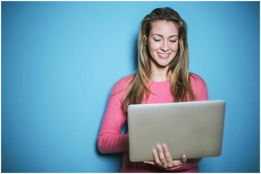Smiling young woman with laptop against blue backg