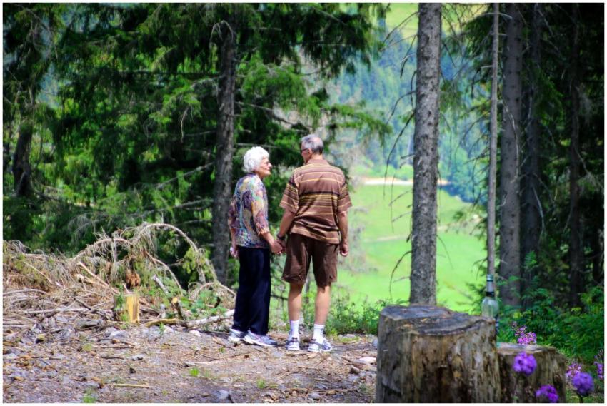 An elderly couple holding hands strolls through a
