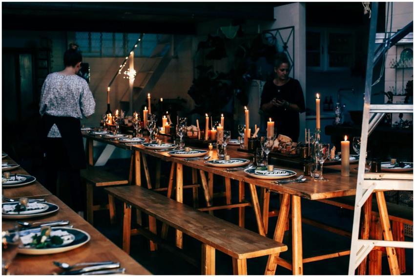 Anonymous women serving wooden tables with plates
