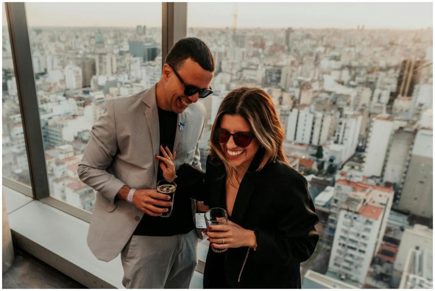 A joyful couple enjoying drinks on a rooftop with