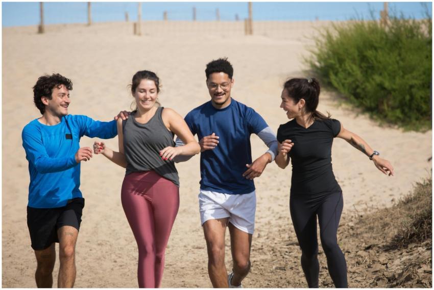 Four friends enjoying a sunny day run on a sandy b