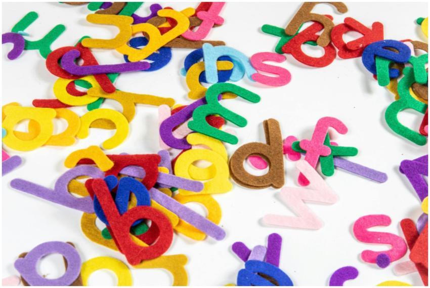 Bright and colorful felt letters scattered on a wh