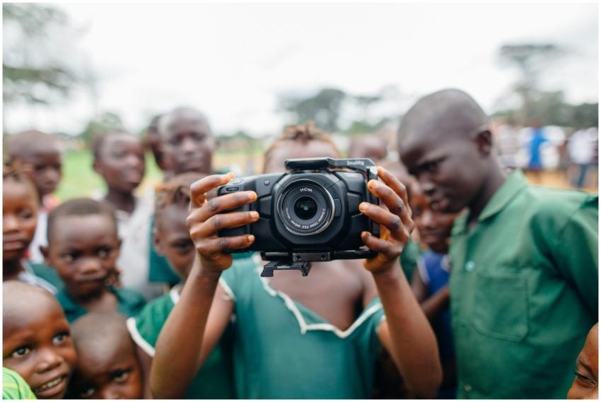 Group of children curiously using a camera outdoor