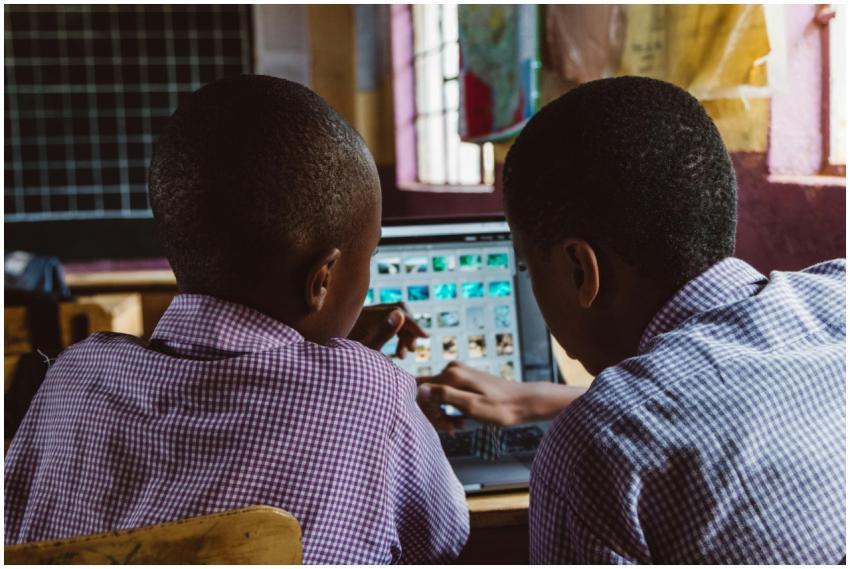 Two schoolchildren in uniform collaborate on a lap