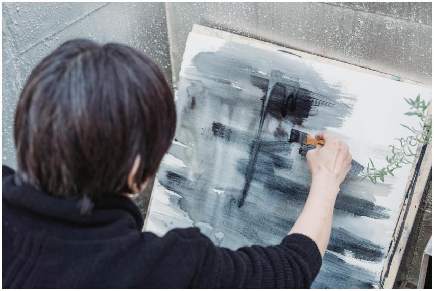 A person painting abstract art on canvas outdoors