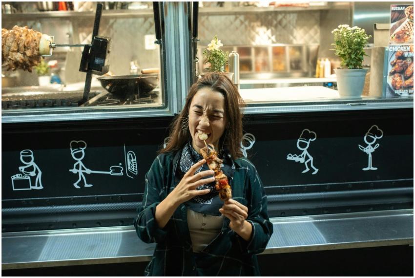Smiling woman biting into a delicious kebab at a v