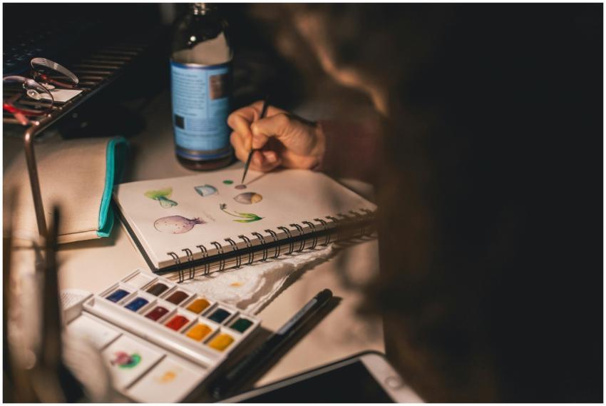 Artist painting with watercolors in a notepad at a