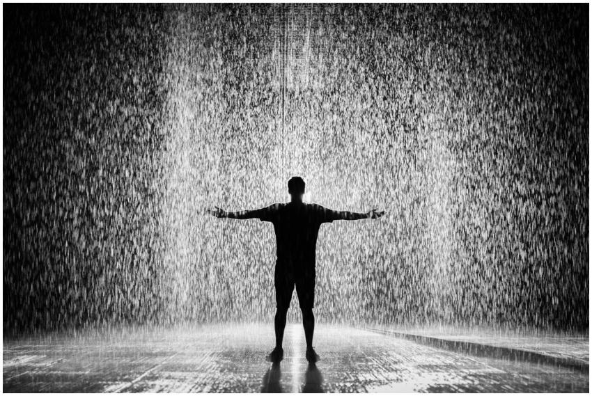 A person joyfully standing in the rain with arms w