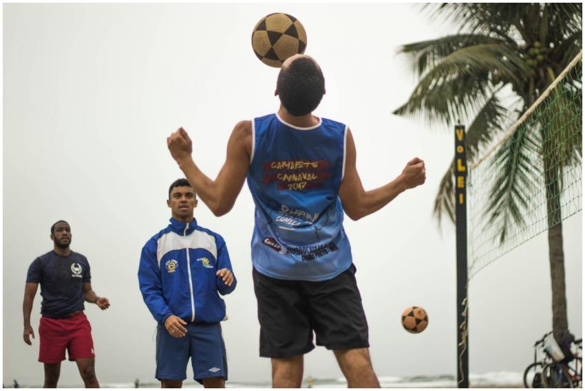 Three men playing a volleyball game on the beach w