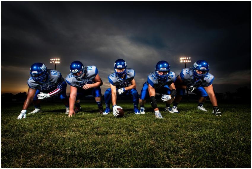 A cohesive football team lines up on the field und