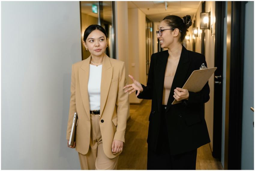 Two businesswomen converse while walking through a