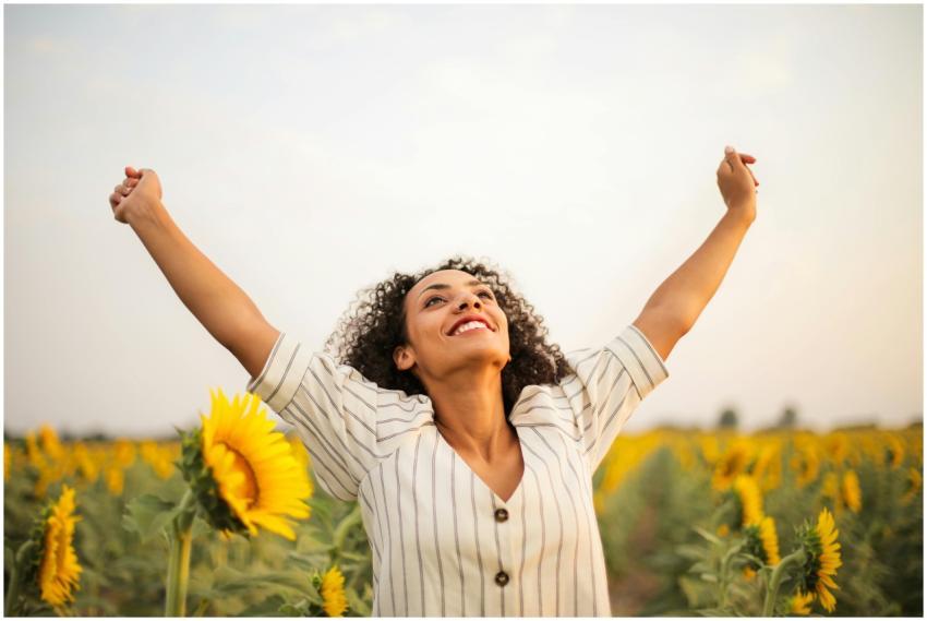 Joyful woman with arms raised in a sunflower field