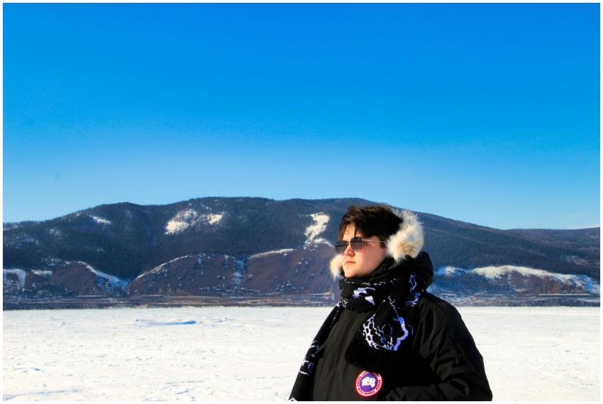A woman in winter clothing stands before a snow-co
