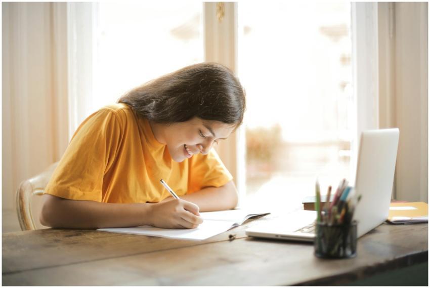 Young woman studying with a laptop and notepad at