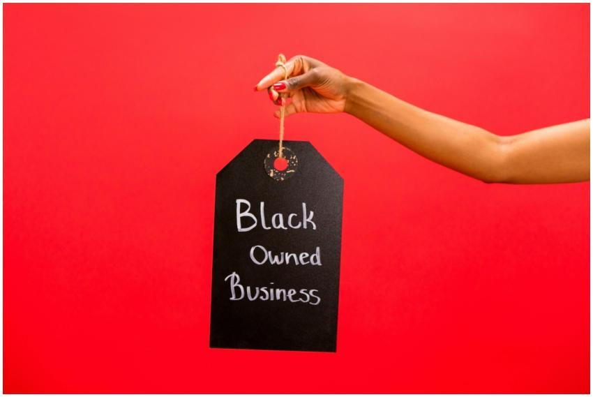 A hand holding a Black Owned Business sign against