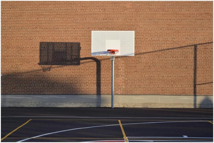 Empty outdoor basketball court with hoop and shado