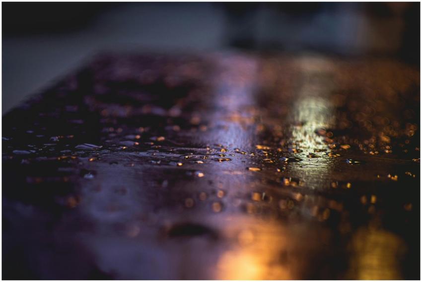 Dark, moody image of raindrops creating reflection