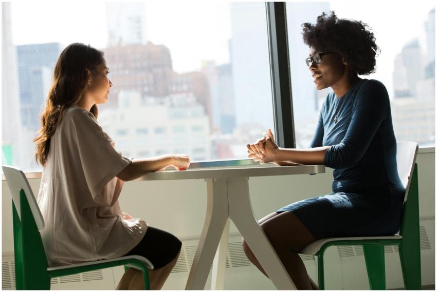Two women sitting and talking at a table with a ci