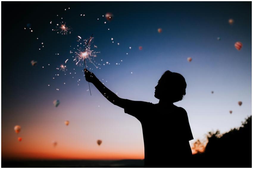 Silhouette of a person holding sparklers against a